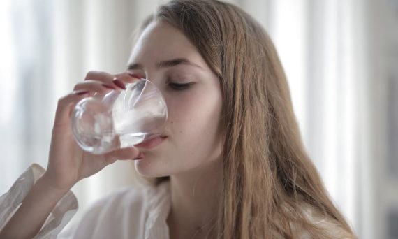A woman enjoying a refreshing glass of water indoors during the day.
